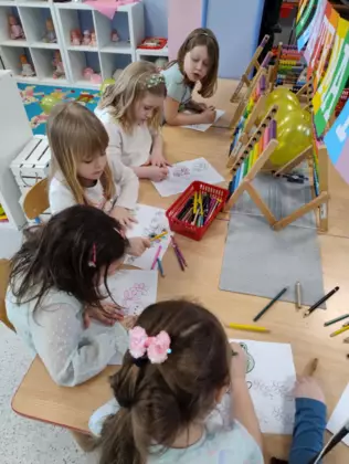 Przedszkolaki kolorują wiosenne obrazki.