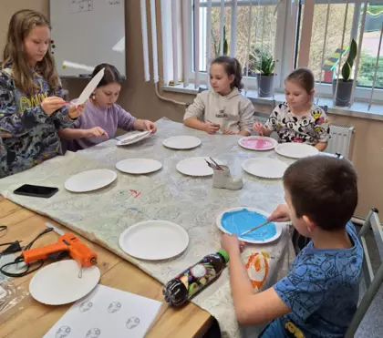 Dzieci malują talerzyki papierowe farbkami.