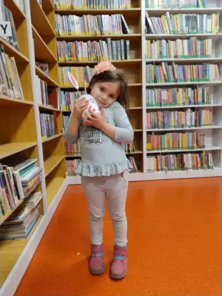 Dziewczynka przytula swoją prace plastyczną