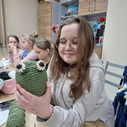 Uczestniczka zajęć pokazuje wyszydełkowaną żabę.
