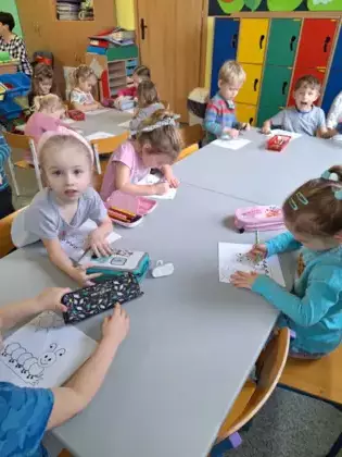 Przedszkolaki kolorują obrazek stonogi.