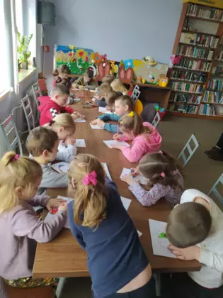 Przedszkolaki przy wspólnym stole kolorują obrazek.