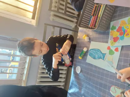 Chłopiec klei serduczka na kartke okolicznościową.