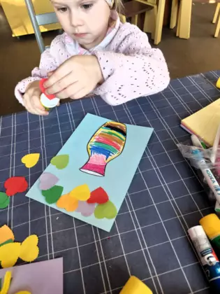 Mała uczestniczka wykańcza kartke na dzień kobiet.