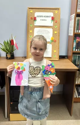 Dziewczynka pozuje  do zdjecia ze swoimi kartkami.