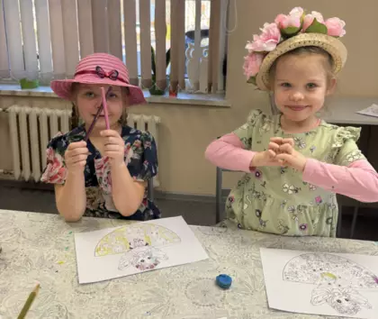 Dziewczynki w kapelusikach na głowie kolorują panią wiosnę.