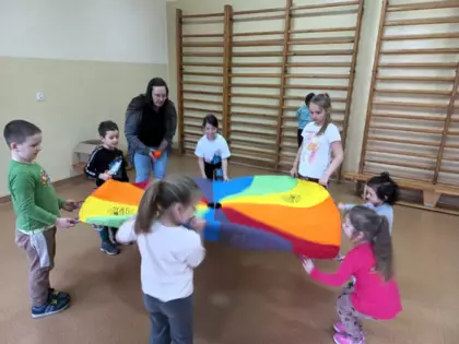 Dzieci bawią się kolorową chustą.