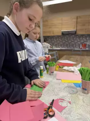 Dziewczynki wycinają kwiatki z papieru.