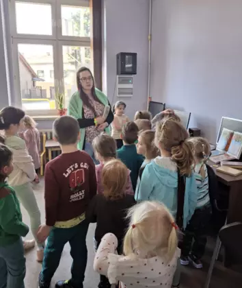 Pani bibliotekarka wita dzieci w bibliotece.