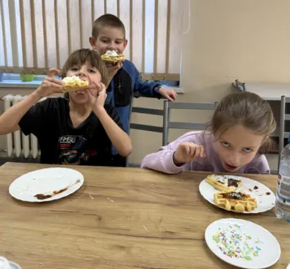 Trójka dzieci zjada gofry.