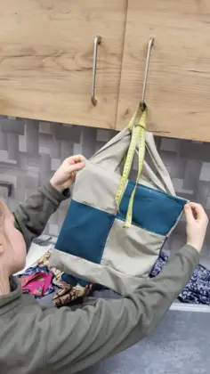 Dziewczyna trzyma w rękach kolorową torbę uszytą na zajęciach.