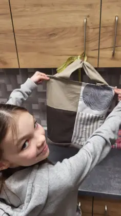 Dziewczyna trzyma w rękach kolorową torbę uszytą na zajęciach.