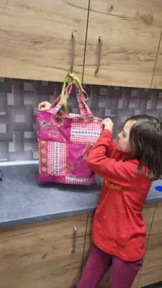 Dziewczyna trzyma w rękach kolorową torbę uszytą na zajęciach.