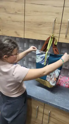 Dziewczyna trzyma w rękach kolorową torbę uszytą na zajęciach.