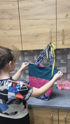 Dziewczyna trzyma w rękach kolorową torbę uszytą na zajęciach.