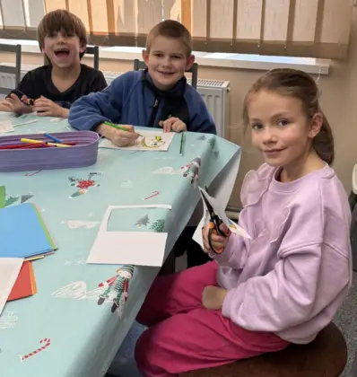 Dzieci wycinają z papieru i kolorują mazakami.