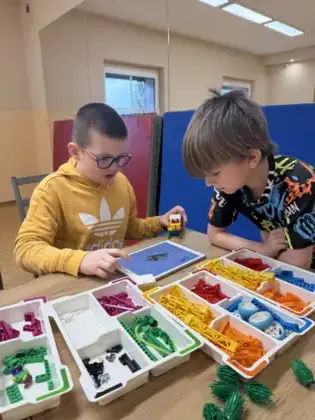 Chłopcy budują z klocków samochody.