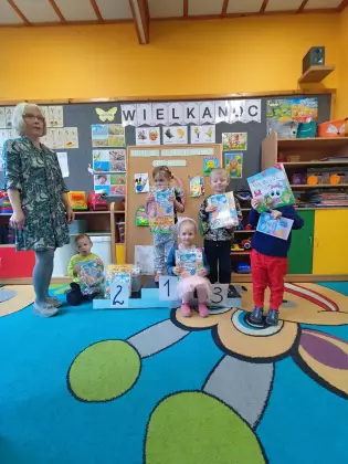 Dzieci stoją na podium w rękach trzymając nagrody.