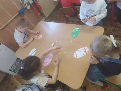 Przedszkolaki wyklejają jajka wielkanocne.