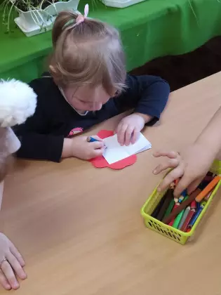 Dziewczynka w przedszkolu maluje obrazek.