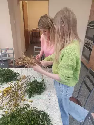 Uczestnicy owijają kółko słomą tworząc wianek.