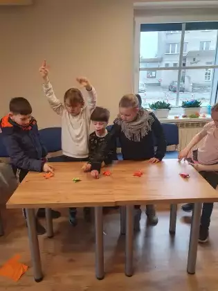 Dzieci bawią się żabkami z papieru, która wyżej skoczy.