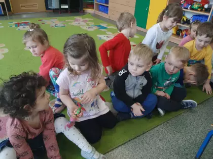 Dzieci siedzą na dywanie o oglądają zabawki.