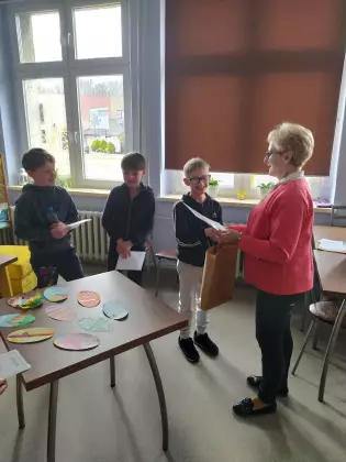 Pani bibliotekarka wręcza dyplomy za udział w konkursie.