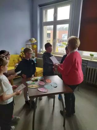 Pani bibliotekarka wręcza dyplomy dzieciom.