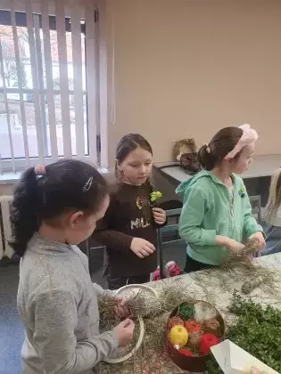 Dziewczynki owijają kółko słomą.