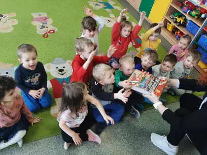 Dzieci siedzą na dywanie i oglądają książki.