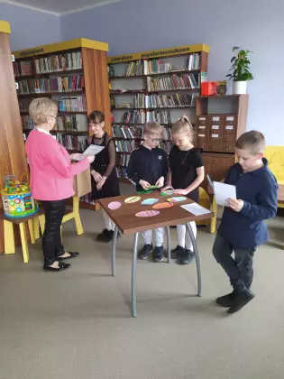 Pani bibliotekarka wręcza dyplomy dzieciom.