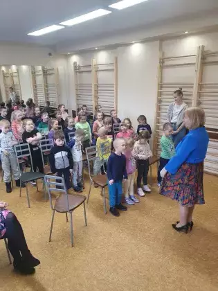 Dzieci stoją na sali i naśladują autorkę spotkania.