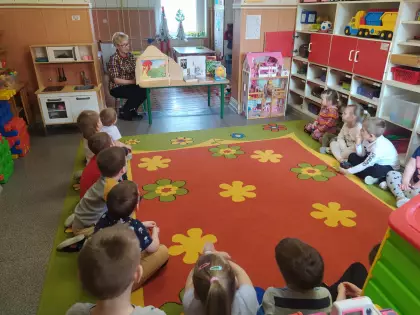 Przedszkolaki siedzą na dywanie i słuchają teatrzyku.