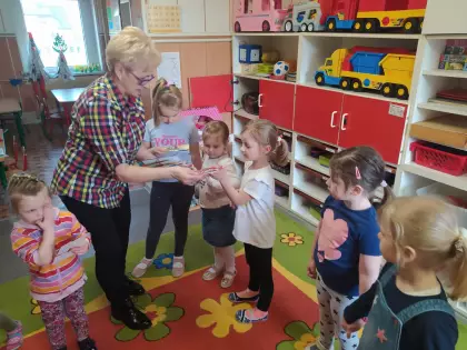 Dzieci stoją na dywanie i odbierają nagrody.