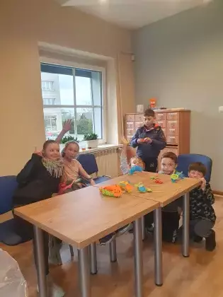 Dzieci siedzą przy stole i pozują do zdjęcia.