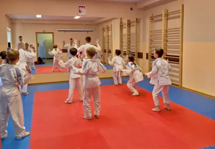 Uczestnicy zajęć wraz z treneren wykonują ćwiczenia przed lustrem.