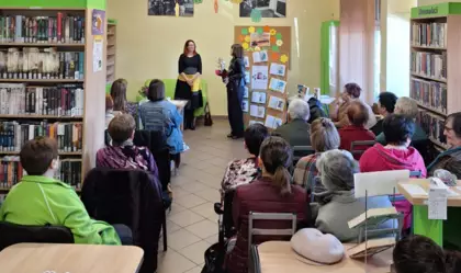 Pani Dyrektor wręcza kwiaty autorce. Z tyłu siedzą uczestnicy spotkania.