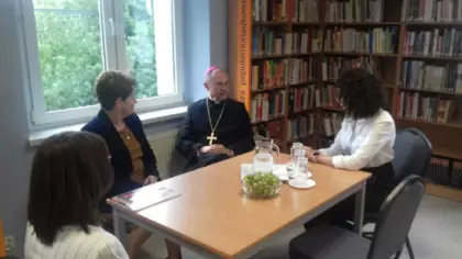 Przy stole w bibliotece siedzą Ks. Biskup Sławomir Oder, Wójt Gminy Pawonków Joanna Wons-Kleta oraz Dyrektor Biblioteki Klaudia Kubica i Pani bibliotekarka.