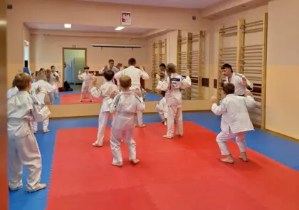 Uczestnicy zajęć wraz z treneren wykonują ćwiczenia przed lustrem.