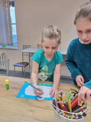 Dziewczynki wykonuje pracę plastyczną - łabędzia z płatków kosmetycznych.