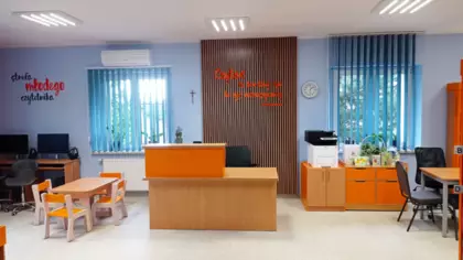 Wypożyczalnia. Na środku stoi biurko a z lewej strony są komputery i kącik dla dzieci.