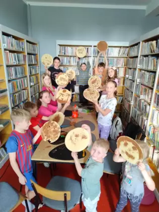Wspólne zdjęcie po zajęciach. Uczestnicy trzymają w rękach wafle pomalowane roztopioną czekoladą.