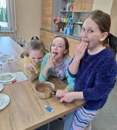 Dziewczyny wylizują czekoladę z garnka.