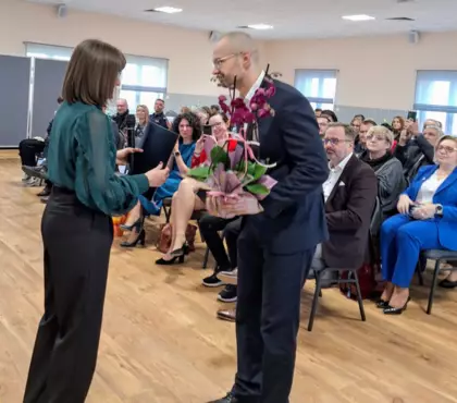 Z przodu Dyrektor Biblioteki wręcza kwiaty Dr Piotrowi Wojtulkowi. Z tyłu siedza uczestnicy otwarcia muzeum.