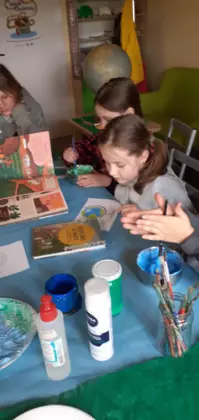 Dzieci mieszają farbę i oglądają książki.