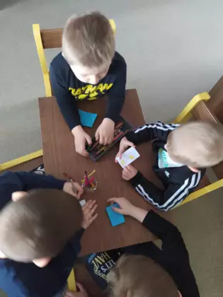 Chłopcy wykonują prace plastyczną - małe kolorowe książeczki.