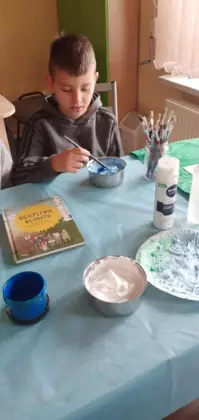 Chłopak miesza farbę w miseczce.