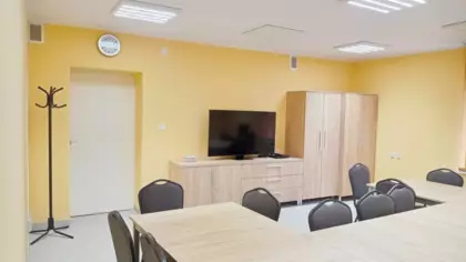 W pokoju seniora znajdują się stoliki z krzesełkami, biurko, komputer oraz szafa.