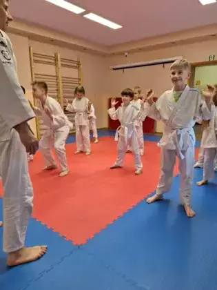 Uczestnicy wspólnie z trenerem ćwiczą przysiady